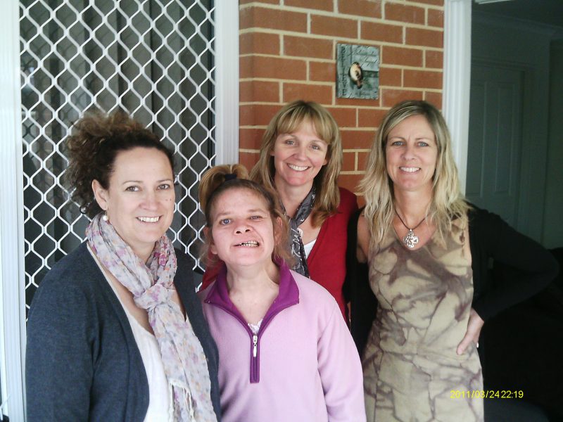 Karlene surrounded by 3 other women at the front of her house. 