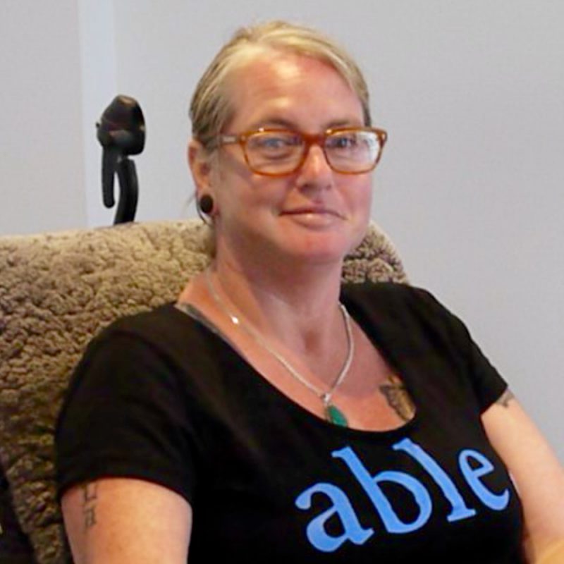 Liz in her own home, wearing a t shirt that says 'able'.